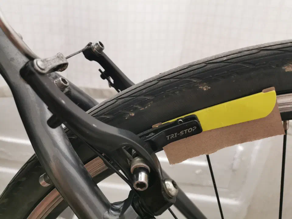 Frein V-Brake en cours de réglage, un morceau de carton glissé entre le patin et la jante