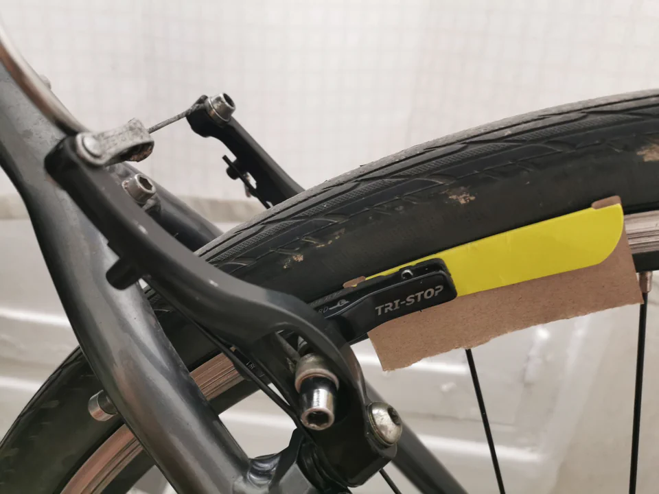 Frein V-Brake en cours de réglage, un morceau de carton glissé entre le patin et la jante