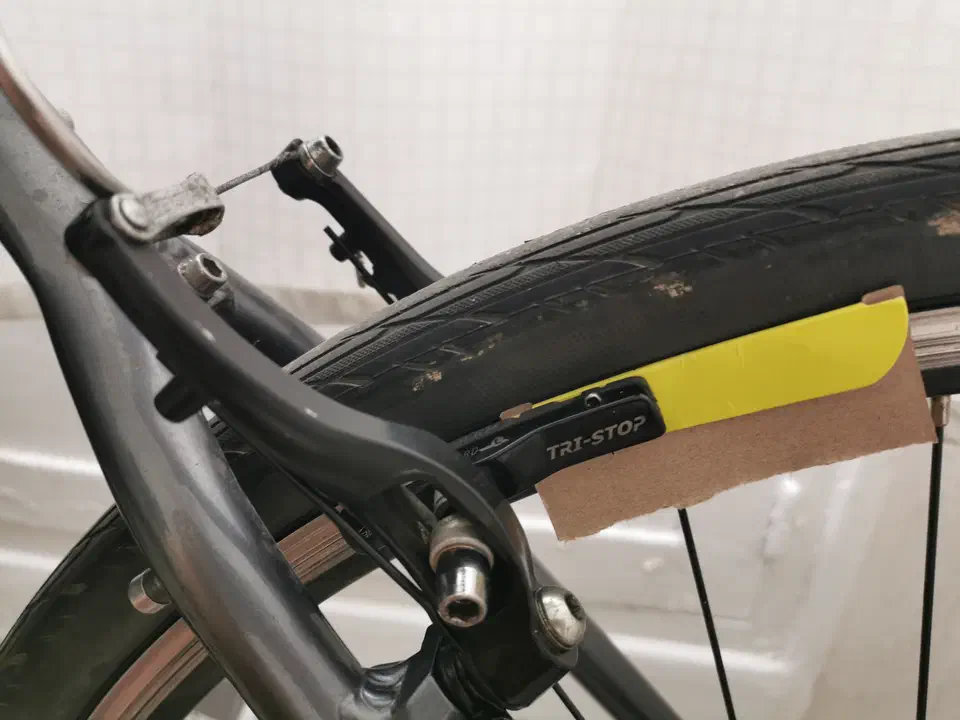 Frein V-Brake en cours de réglage, un morceau de carton glissé entre le patin et la jante